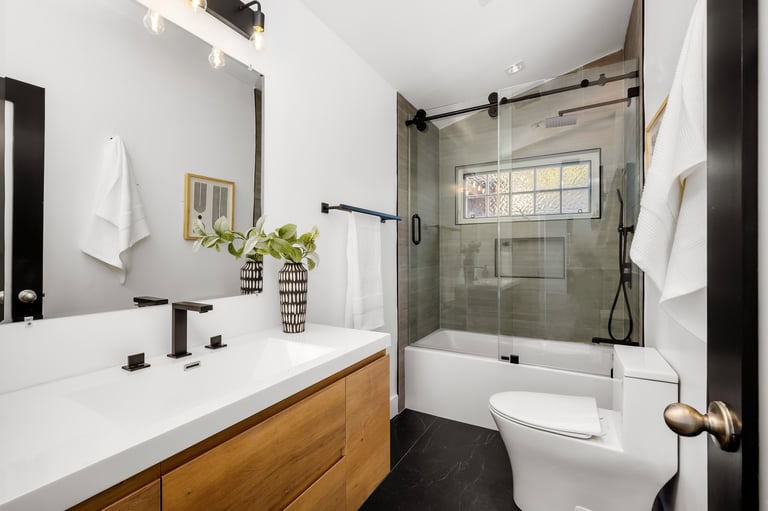 Secondary bathroom with tub-shower combination, single vanity, clean neutral tile, and functional family-friendly design