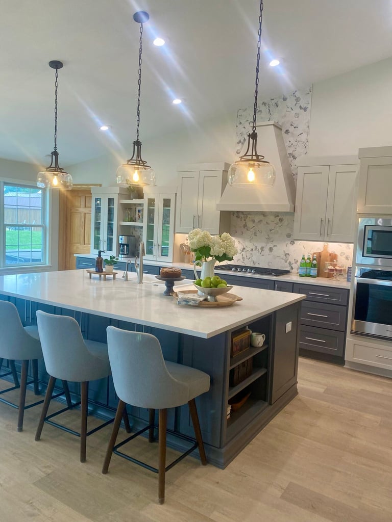 Modern kitchen with large island, white quartz countertops, teal base cabinets, glass-front upper cabinets, and pendant lighting overhead