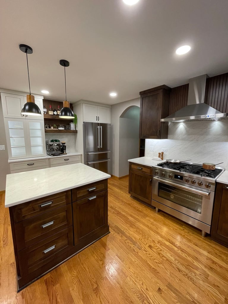 Modern kitchen with dark wood cabinetry, white marble island, stainless steel appliances, and wood flooring