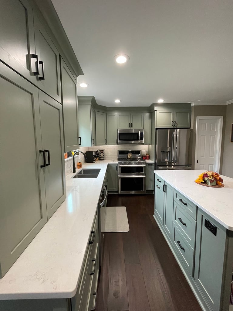 Modern kitchen with light blue cabinets, white quartz countertops, stainless steel appliances, dark wood flooring, and recessed lighting