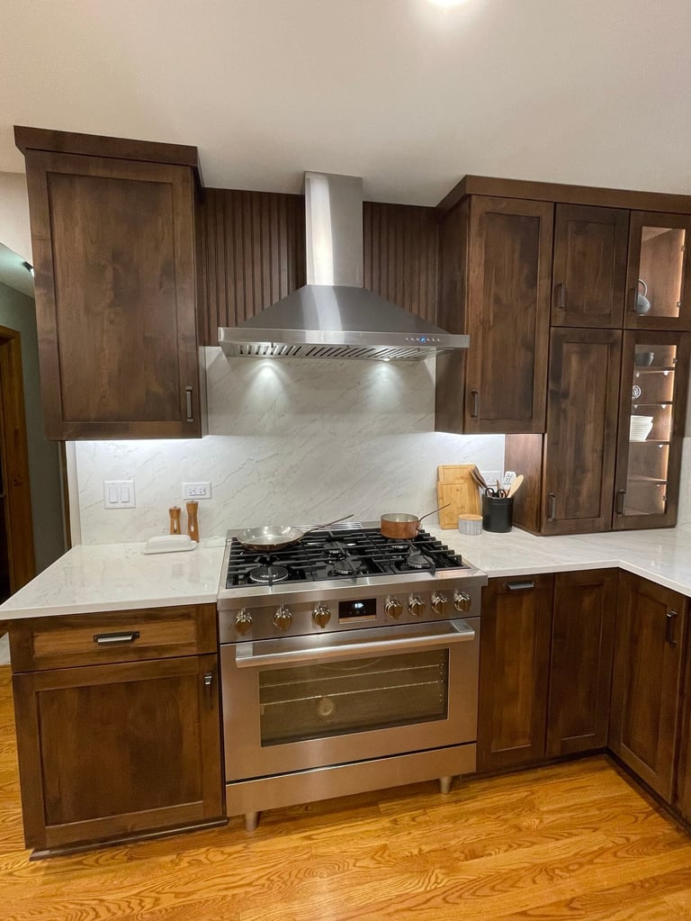Modern kitchen with marble countertops, stainless steel range, and dark wood cabinetry with range hood above