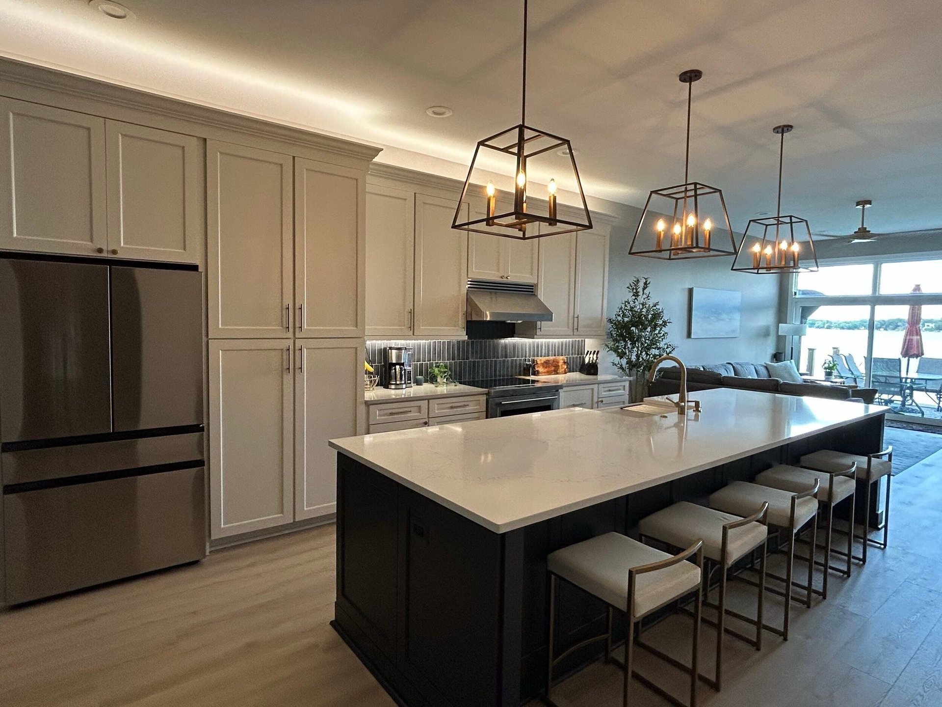 Modern kitchen with cream cabinetry, black island with white countertop, pendant lights, and ocean view windows