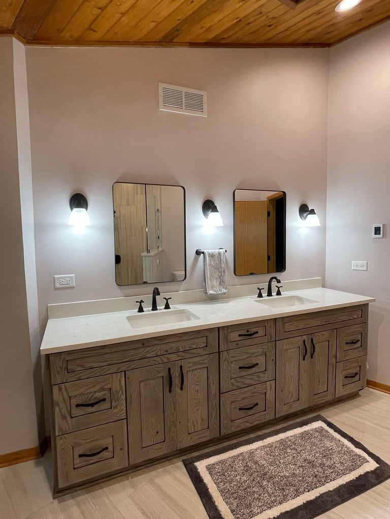 Modern bathroom with dual vanity sink, wooden cabinetry, framed mirrors, and wall-mounted sconces with wooden ceiling